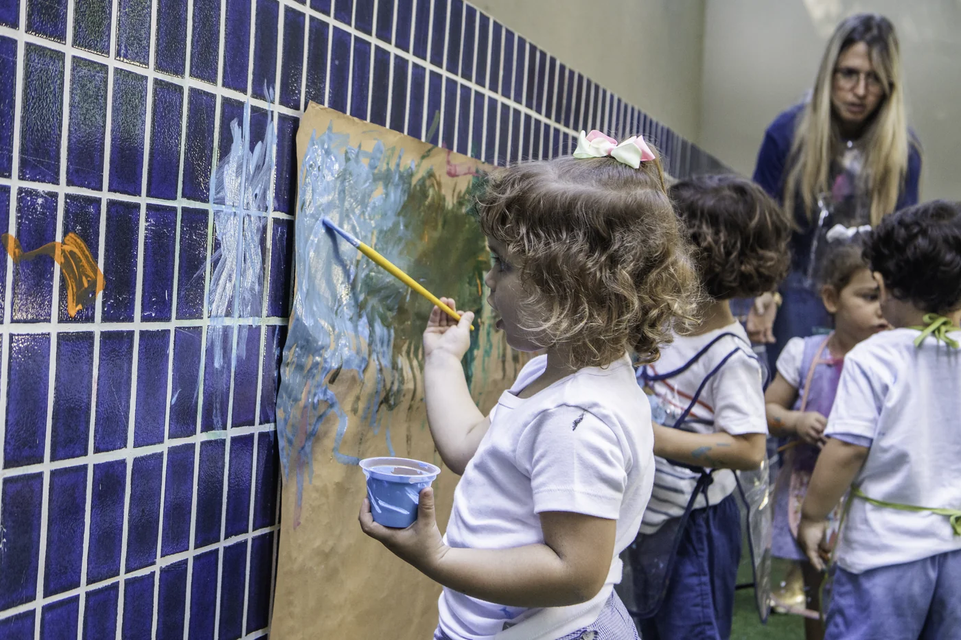 Criança pintando um mural na parede de azulejos