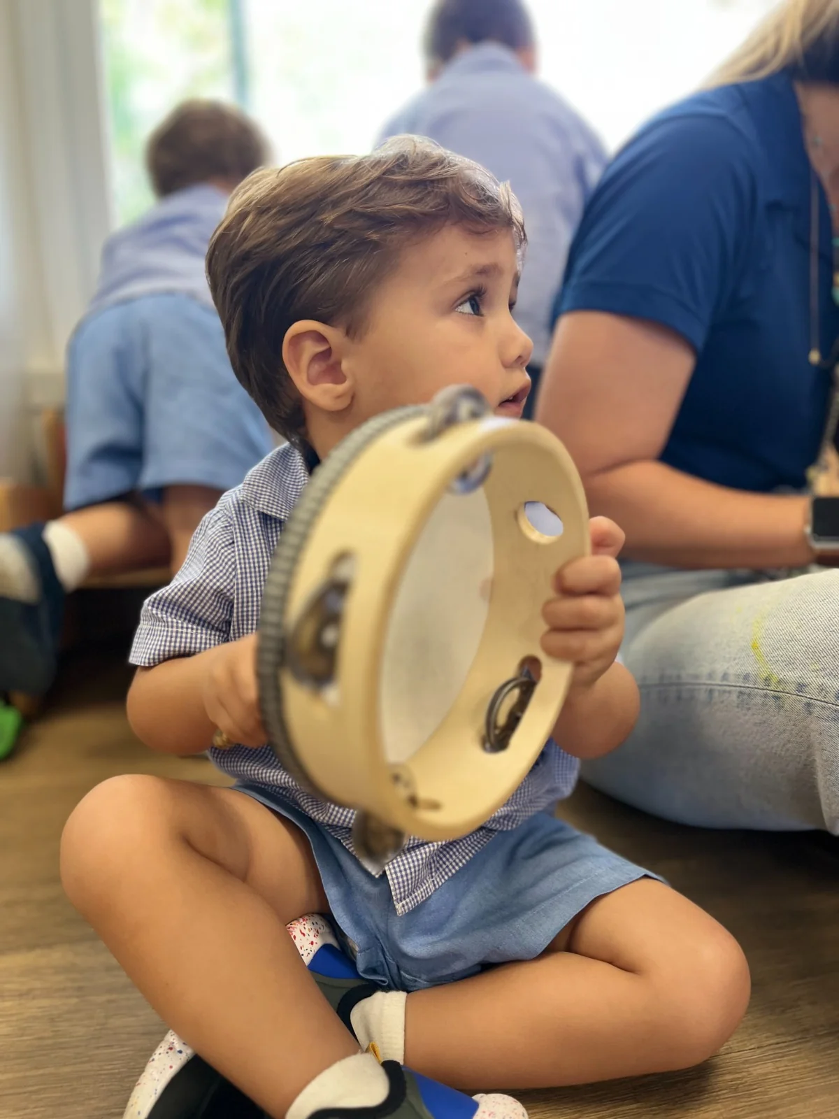 Criança explorando pandeiro no ateliê de musicalização
