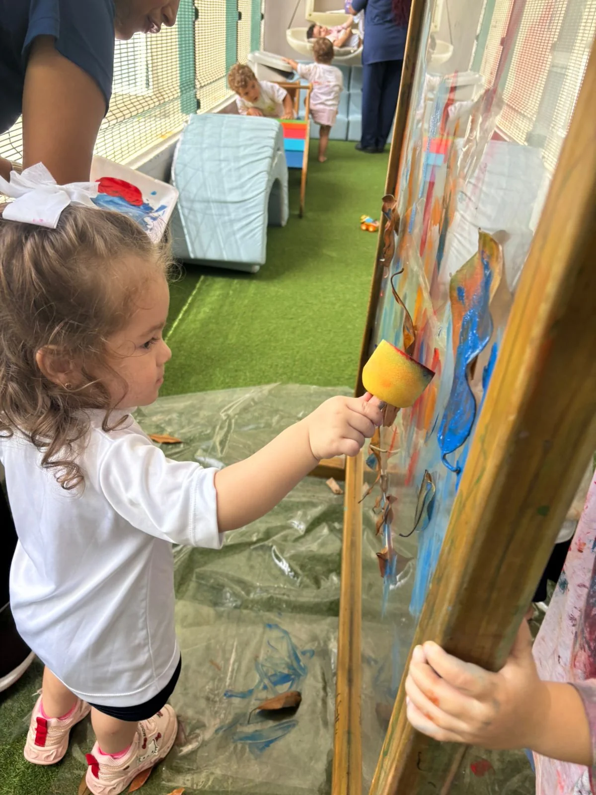 Criança pintando em cavalete com rolo