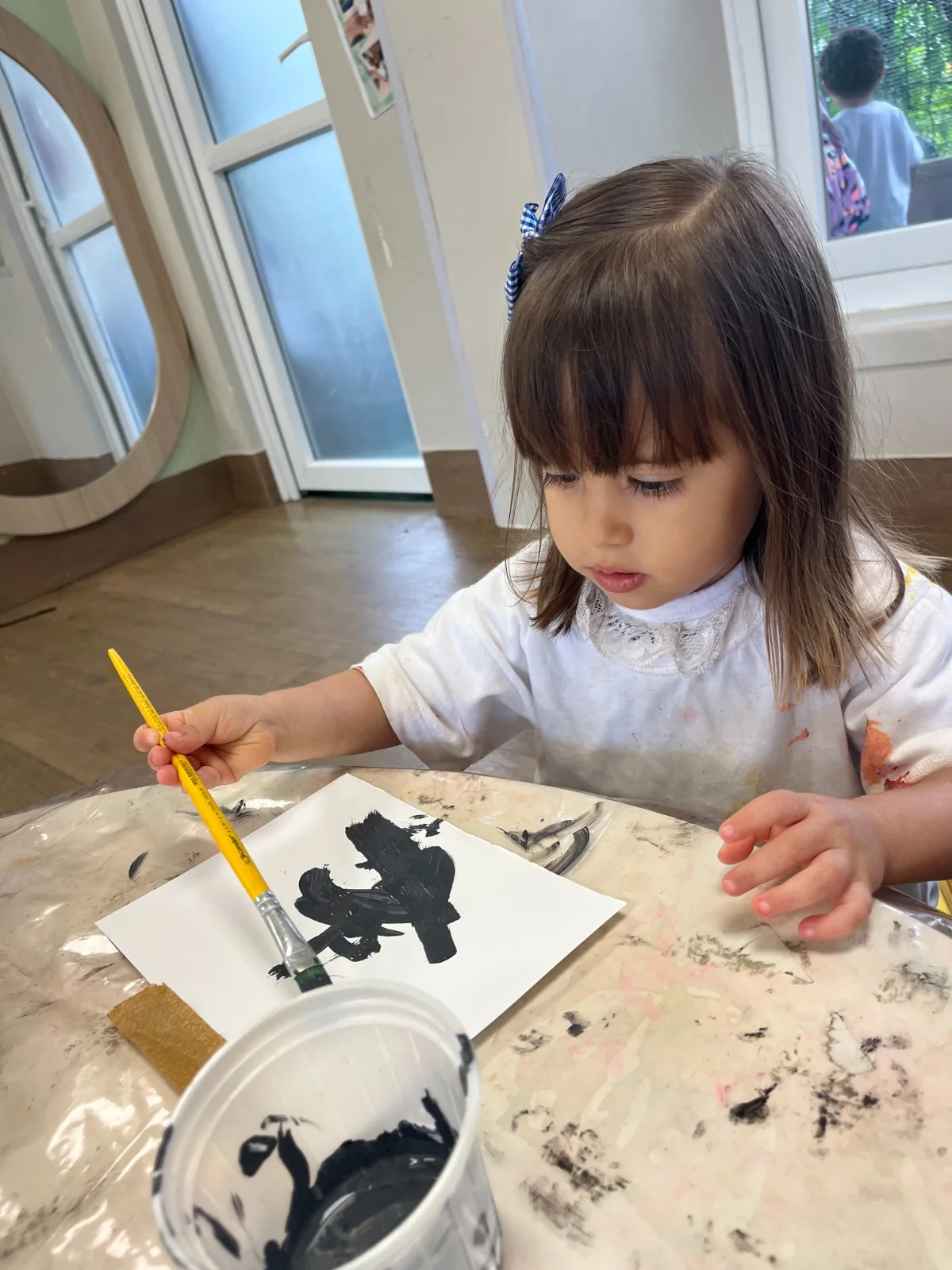 Close de criança pintando com tinta preta